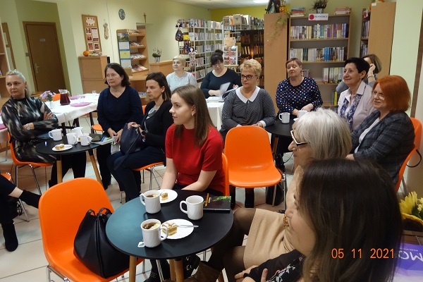 W bibliotece przy okrągłych stolikach siedzą kobiety i jeden mężczyzna.